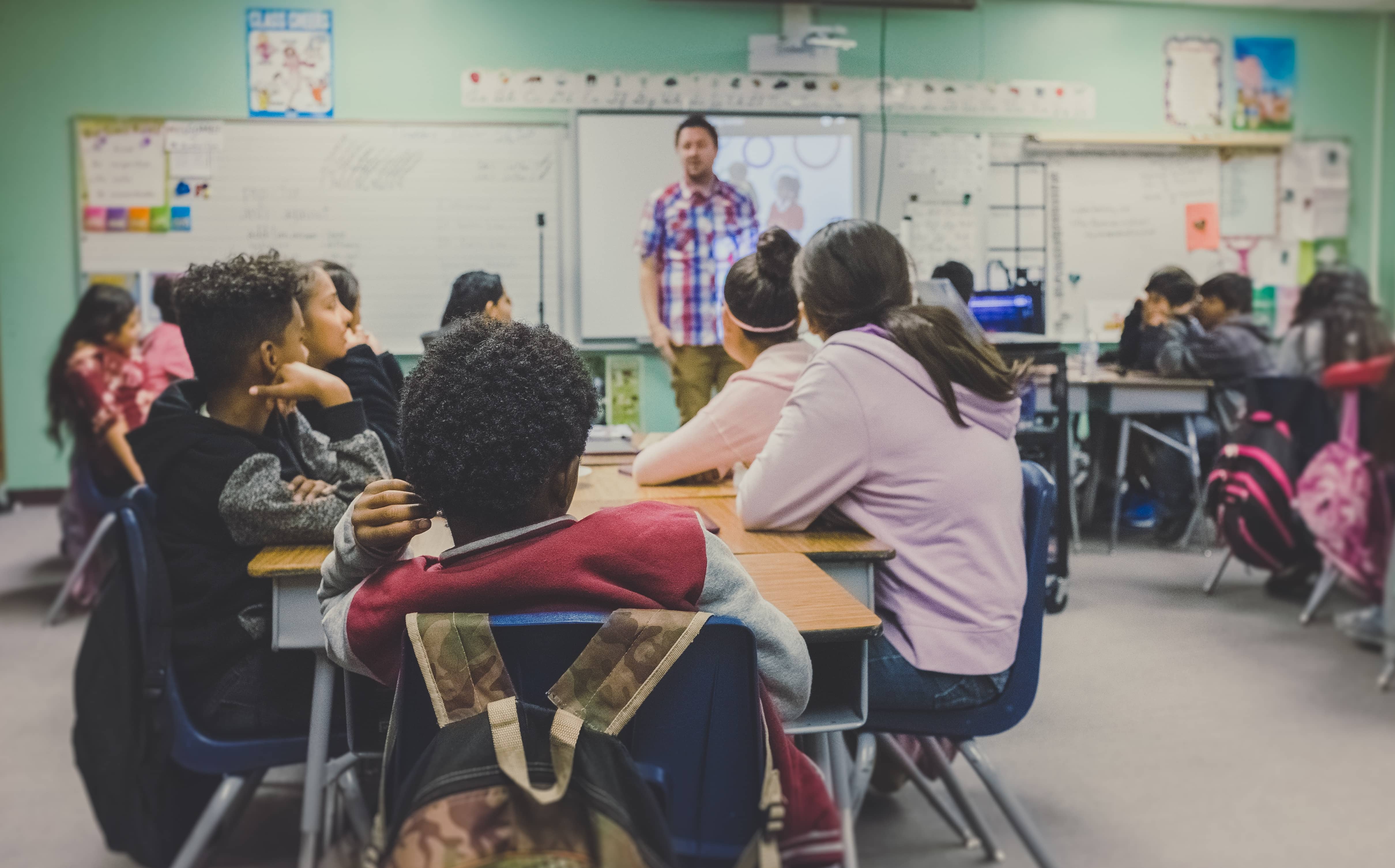 Students in a classroom looking at a teacher.